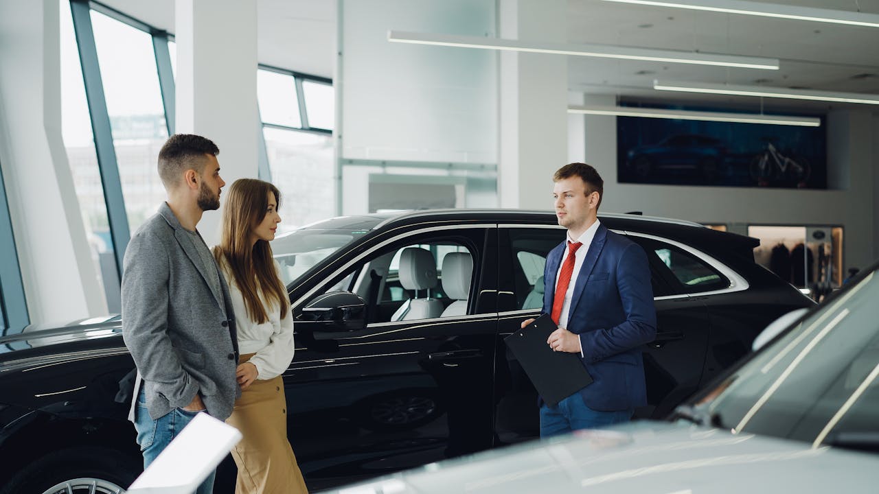 Salesperson assisting couple in modern car showroom.