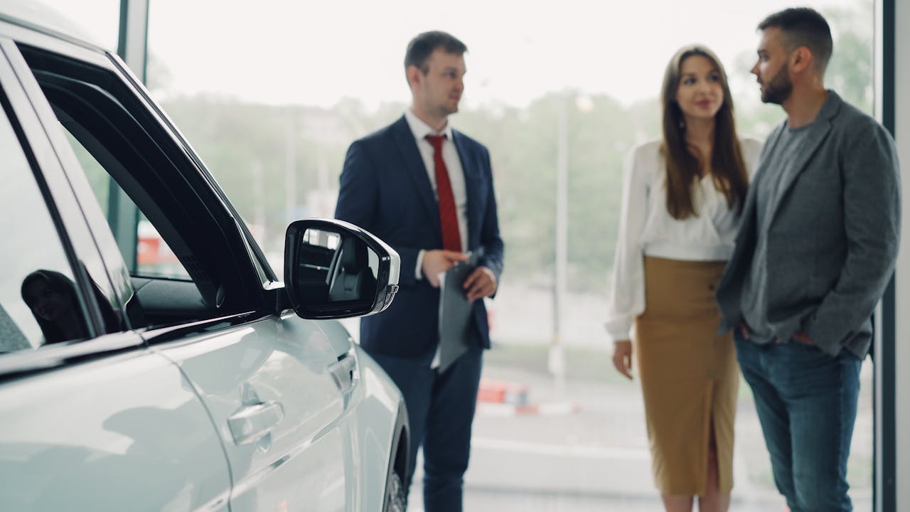 Salesperson consulting couple in a modern car showroom.